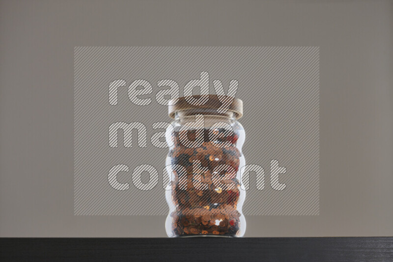 Sequins in a glass jar on black background