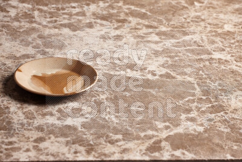 A multicolored pottery plate on beige marble background