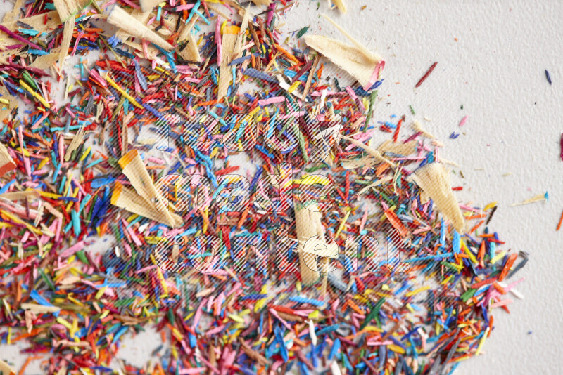 This image showcases a vibrant multicolored pencil shavings scattered on grey background