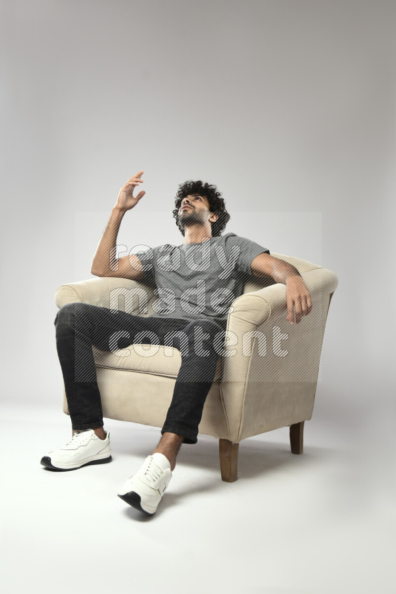 A man wearing casual sitting on a chair making a hand gesture on white background