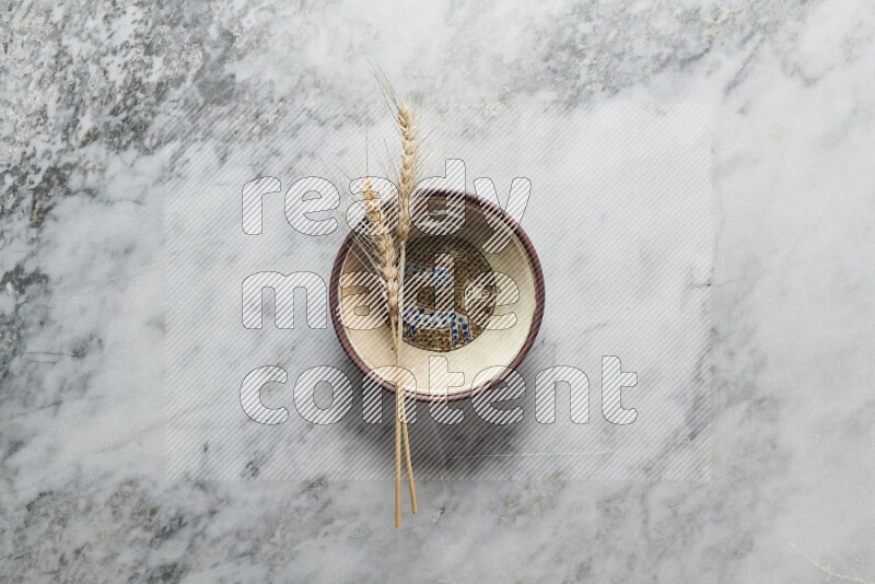 Wheat stalks on decorative pottery plate on grey marble background