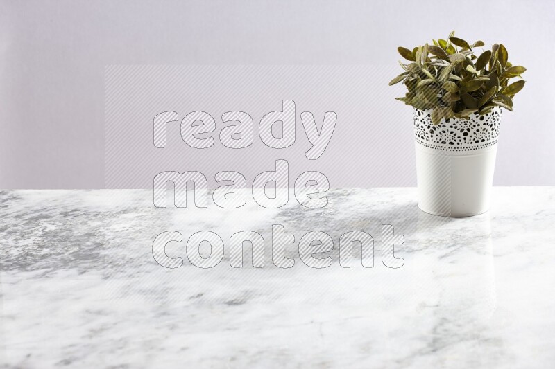 Green artificial plant in white decorative pot on grey marble background