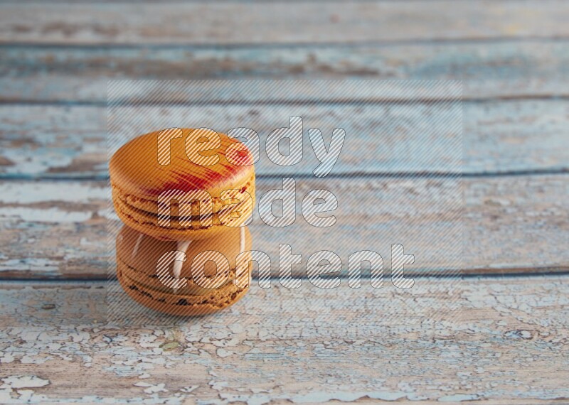 45º Shot of of two assorted Brown Irish Cream, and Orange Exotic macarons on light blue background