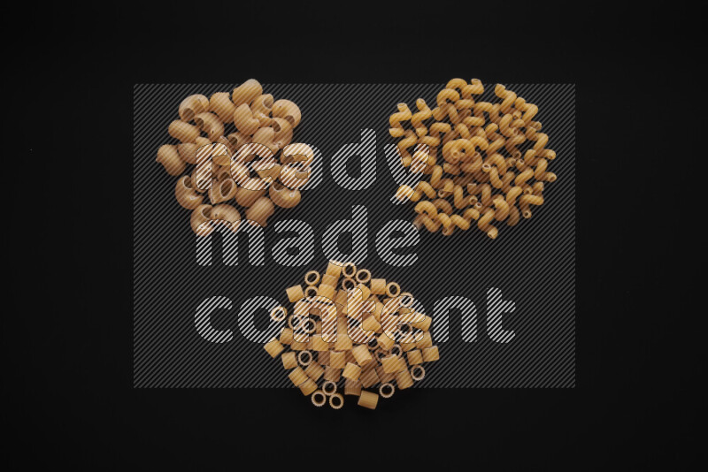 Different pasta types in bunches on black background