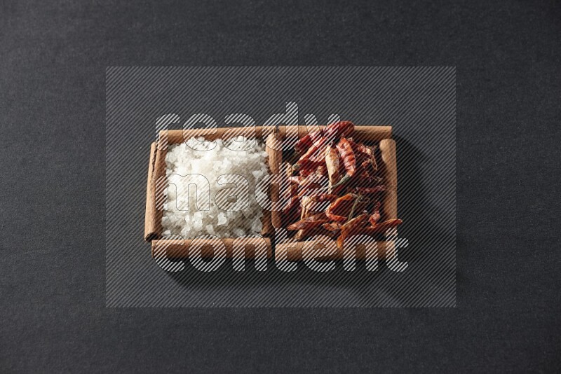 2 squares of cinnamon sticks full of chilis and salt on black flooring