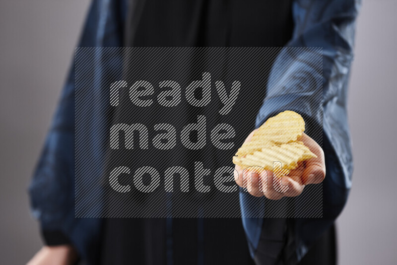 Woman in abaya holding different kinds of snacks in different positions