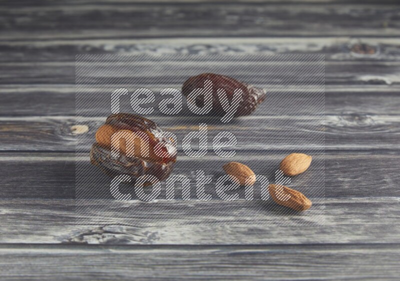 two almond stuffed madjoul dates on a wooden grey background