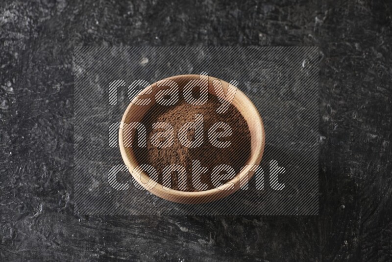 وعاء خشبي ممتلئ ببودرة القرنفل علي خلفية سوداء