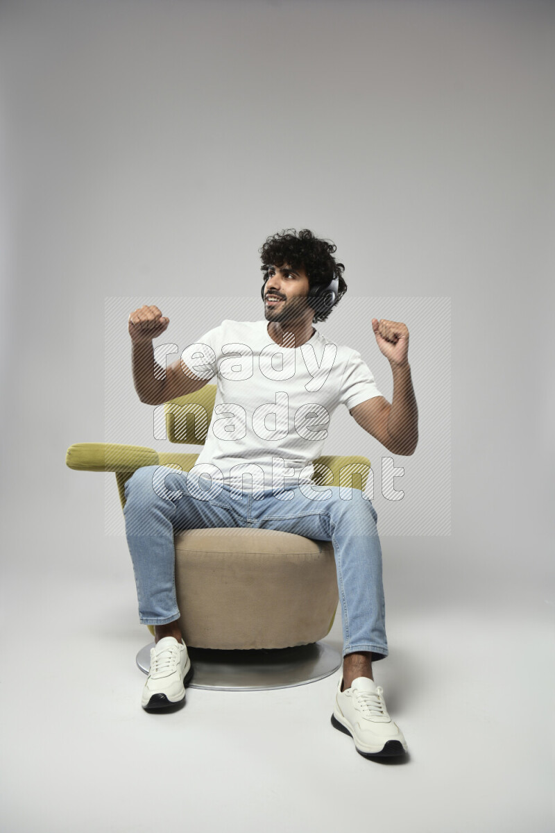 A man wearing casual sitting on a chair putting on headphones on white background