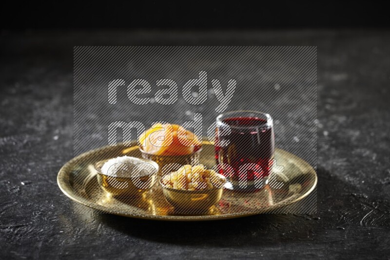 Dried fruits in metal bowls with Hibiscus on a tray in dark setup