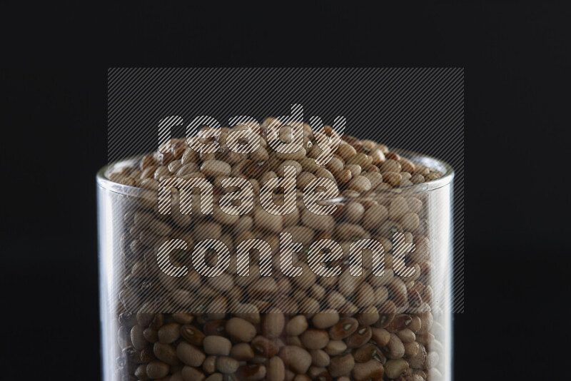 Black-eyed peas in a glass jar on black background