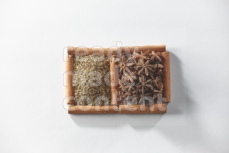 مربعان من أعواد القرفة ممتلئان باليانسون النجمي والكمون علي خلفية بيضاء