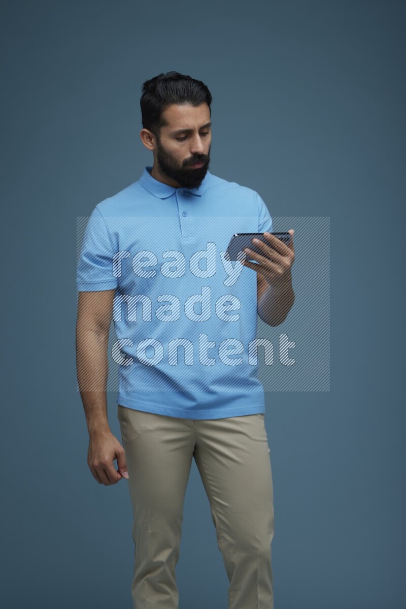 A man Watching a movie on his phone in a blue background wearing a Blue shirt