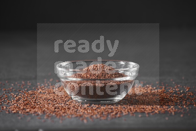 وعاء زجاجي ممتلئ ببذور حب الرشاد محاط بالبذور على أرضية سوداء