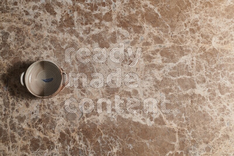 A multicolored pottery bowl on beige marble background