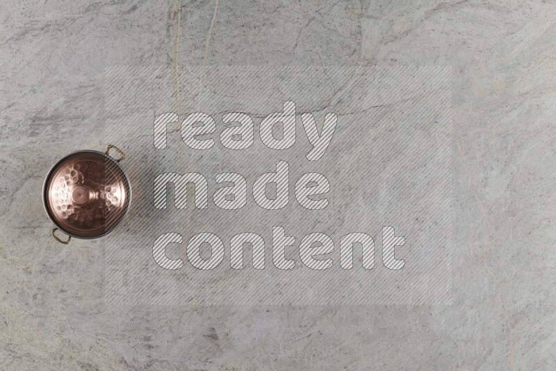 A small copper pot on grey marble background