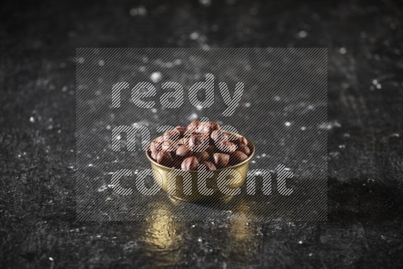 Nuts in a metal bowl in a dark setup