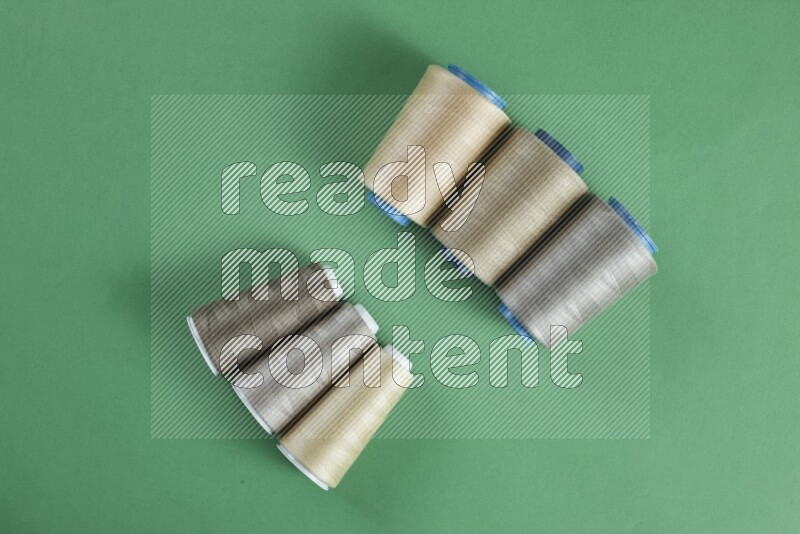 مجموعة من أدوات الخياطة والتفصيل بنية اللون على خلفية خضراء