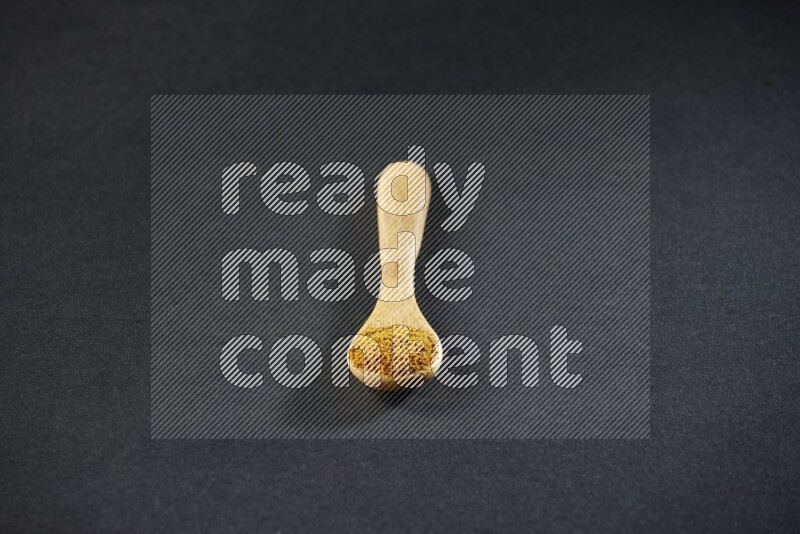 ملعقة خشبية ممتلئة ببودرة الكركم على خلفية سوداء