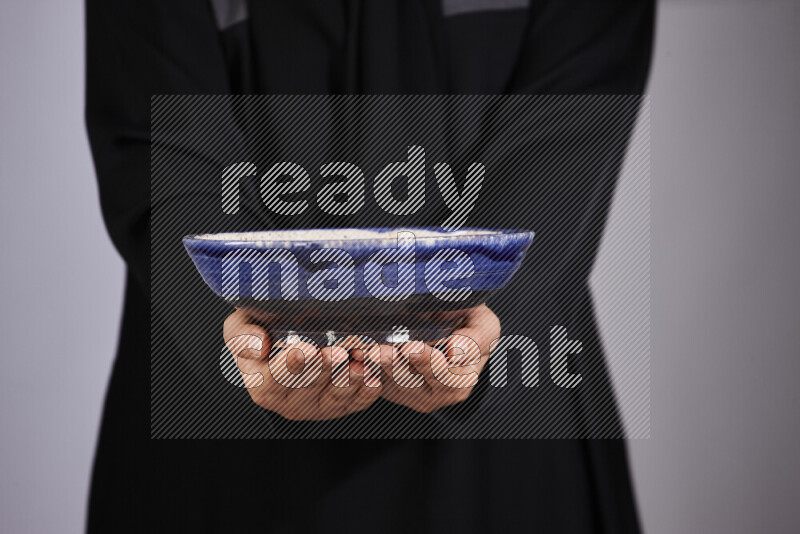 A woman in black abaya holding different pottery essentials in different positions
