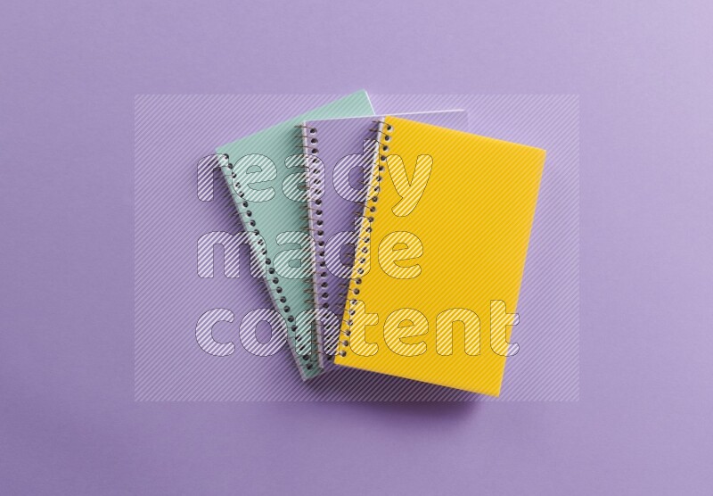 Multicolored notebooks on purple background