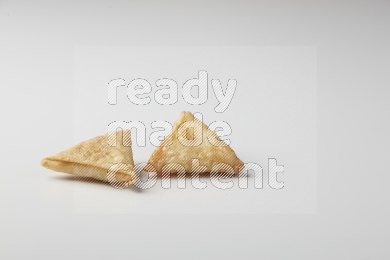 Two fried sambosas on a white background