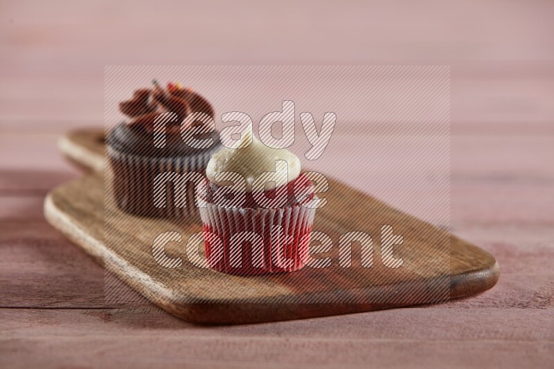 Red velvet mini cupcake topped with cream on a wooden board