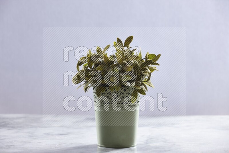 Artificial plant in green decorative pot on grey marble background