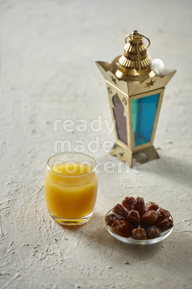 A golden lantern with different drinks, dates, nuts, prayer beads and quran on textured white background
