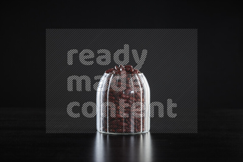 Red kidney beans in a glass jar on black background