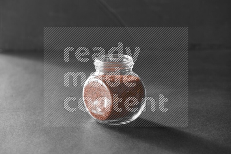 A glass spice jar full of garden cress on black flooring