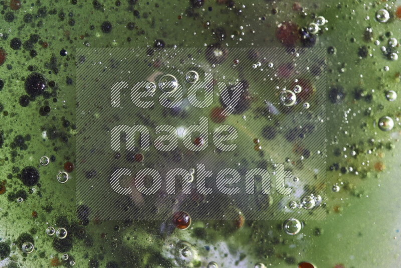 Close-ups of abstract red, green and blue watercolor drops on oil Surface on green background