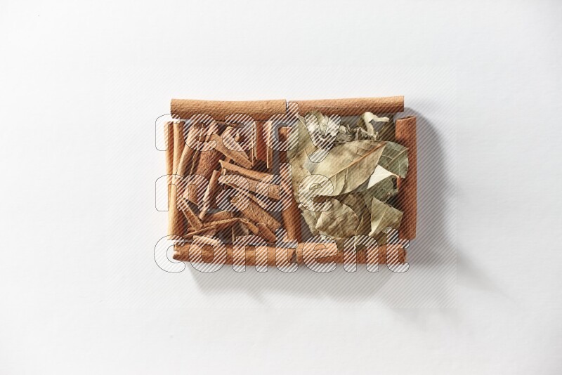 2 squares of cinnamon sticks full of cinnamon and bay laurel leaves on white flooring