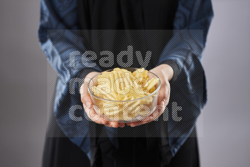 Woman in abaya holding different kinds of snacks in different positions