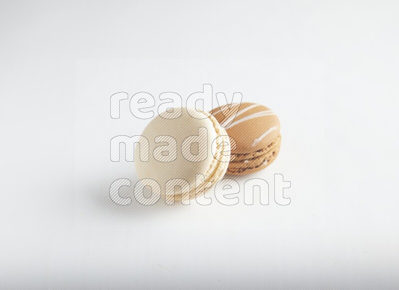 45º Shot of of two assorted Brown Irish Cream, and White Caramel fleur de sel macarons on white background