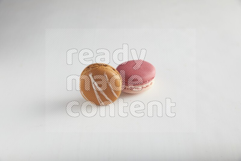 45º Shot of of two assorted Brown Irish Cream, and Pink Litchi Raspberry macarons on white background