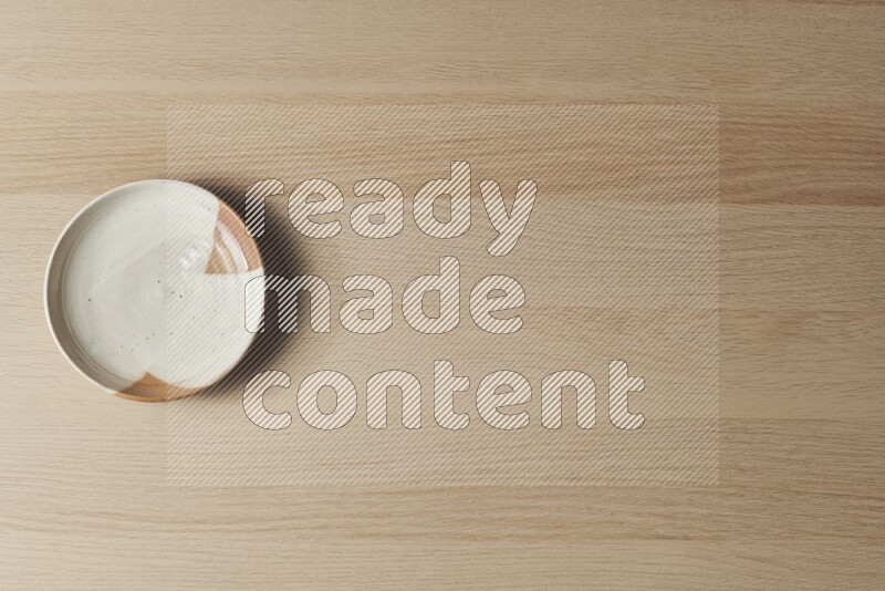 صحن فخاري متعدد الألوان على خلفية خشبية فاتحة