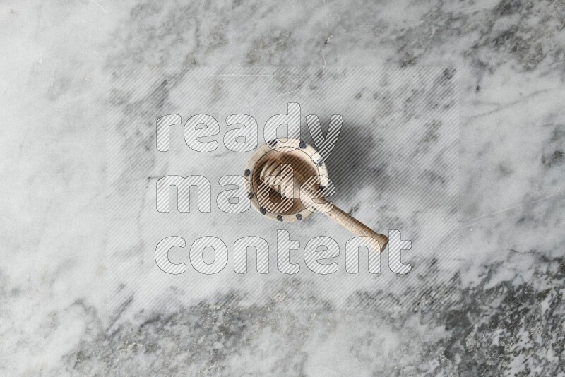 Decorative pottery bowl with wooden honey dipper in it on grey marble background