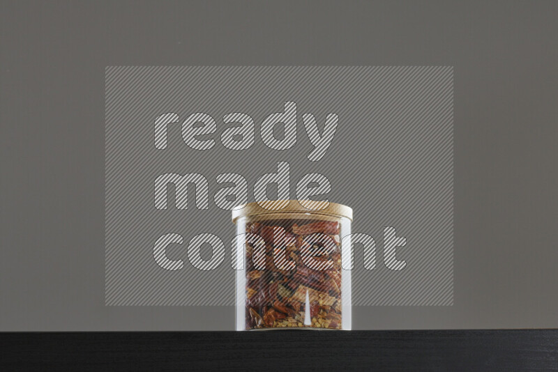 Chili pepper in a glass jar on black background