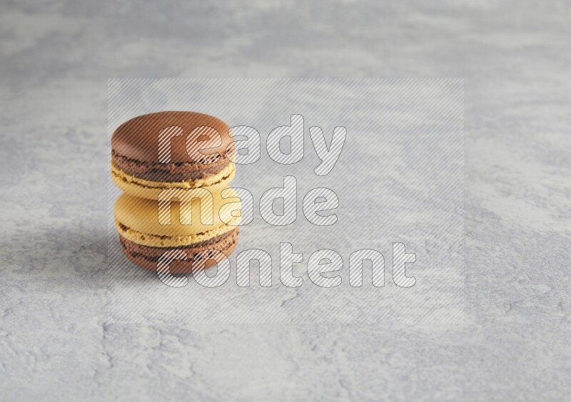 45º Shot of two Yellow and Brown Chai Latte macarons r on white  marble background