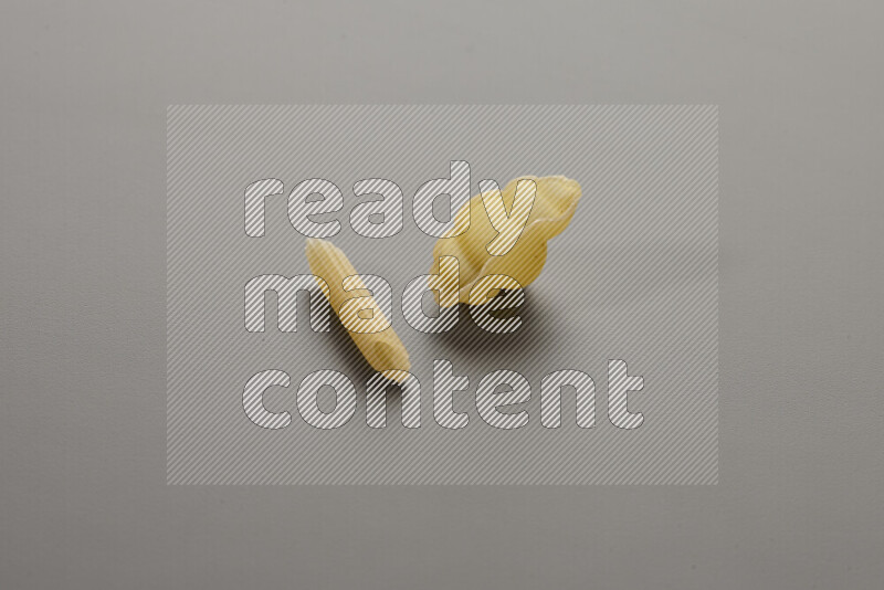 Mini penne pasta with other types of pasta on grey background