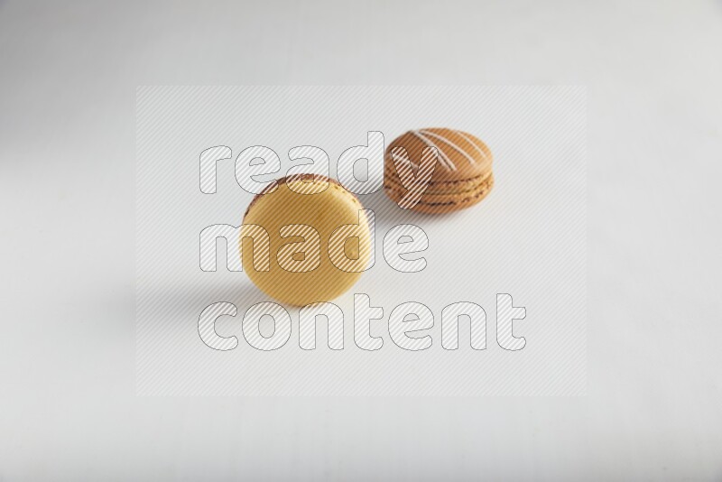 45º Shot of of two assorted Brown Irish Cream, and Yellow, and Brown Chai Latte macarons on white background