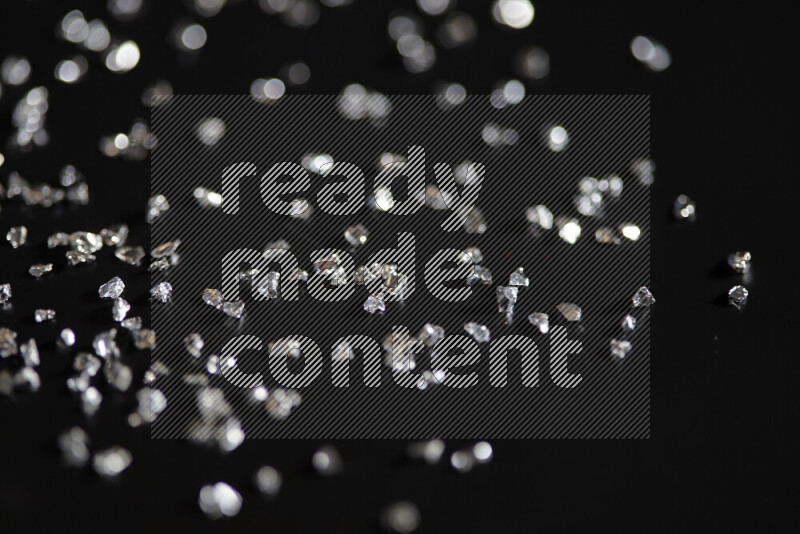 Silver shimmering fragments of glass scattered on a black background