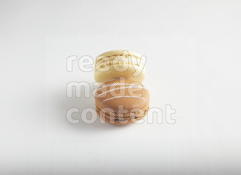 45º Shot of of two assorted Brown Irish Cream, and Yellow Vanilla macarons on white background