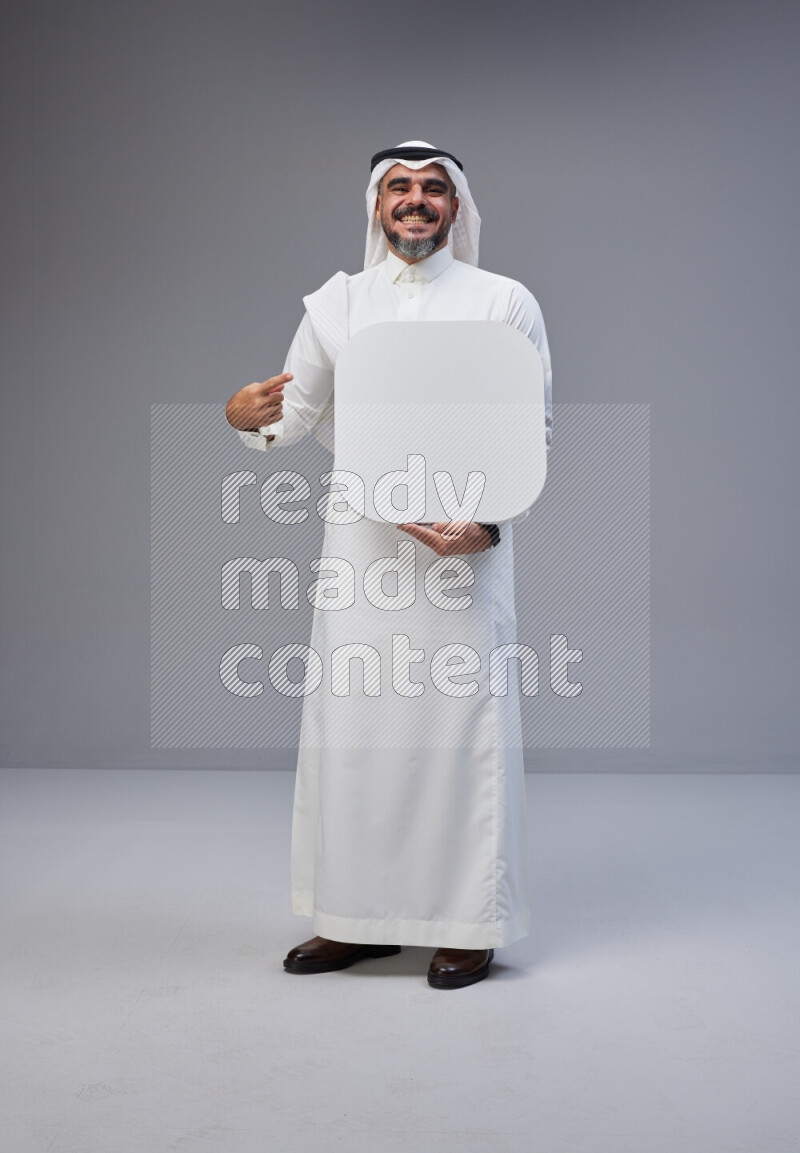 Saudi man Wearing Thob and white Shomag standing holding social media sign on Gray background