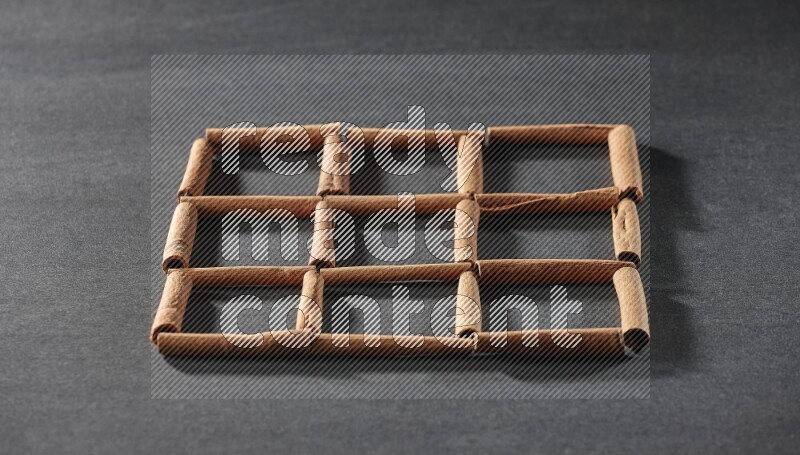 9 empty squares of cinnamon sticks on black flooring