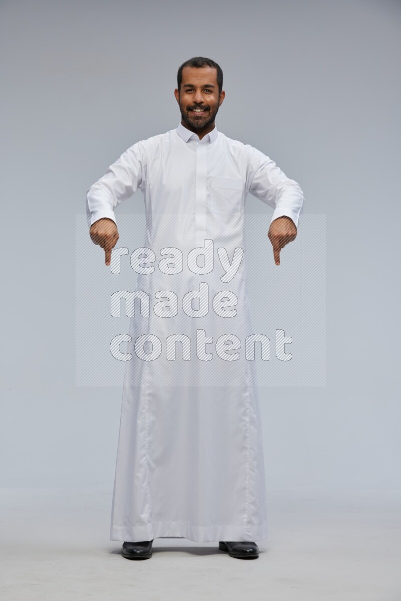 Saudi man Wearing Thob standing interacting with the camera on Gray background