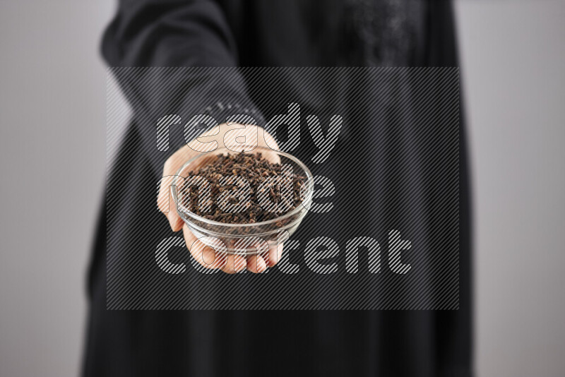Woman in abaya holding different kinds of spices in different positions