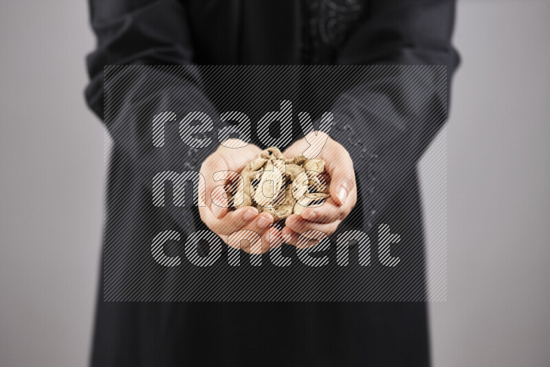 Woman in abaya holding different kinds of spices in different positions