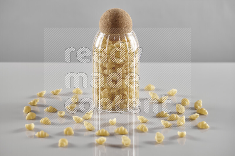 Raw pasta in a glass jar on light grey background